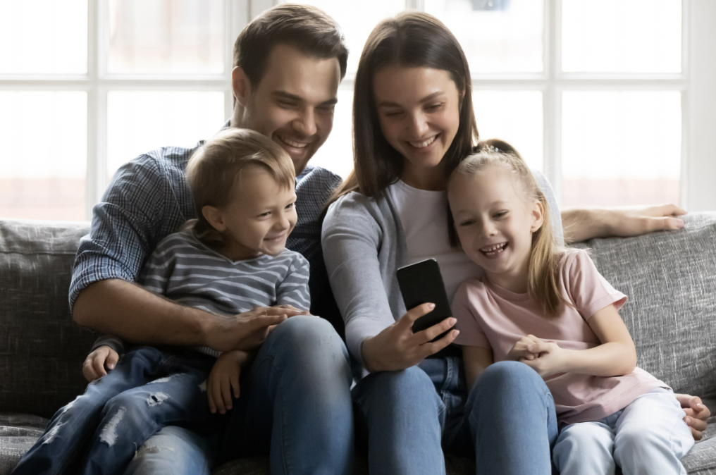 Parents and their children video chatting with someone all together; the parents are including their children in the conversation to not make them feel left out or less important than their parents' phones.